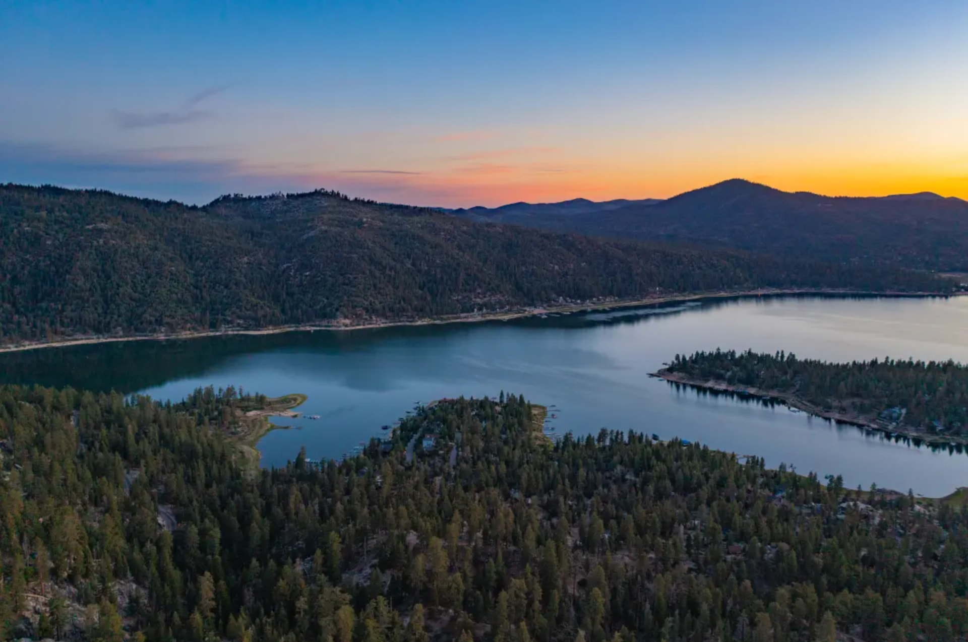 Big Bear Lake viewed from Castle Rock at sunset, framed by pine forest